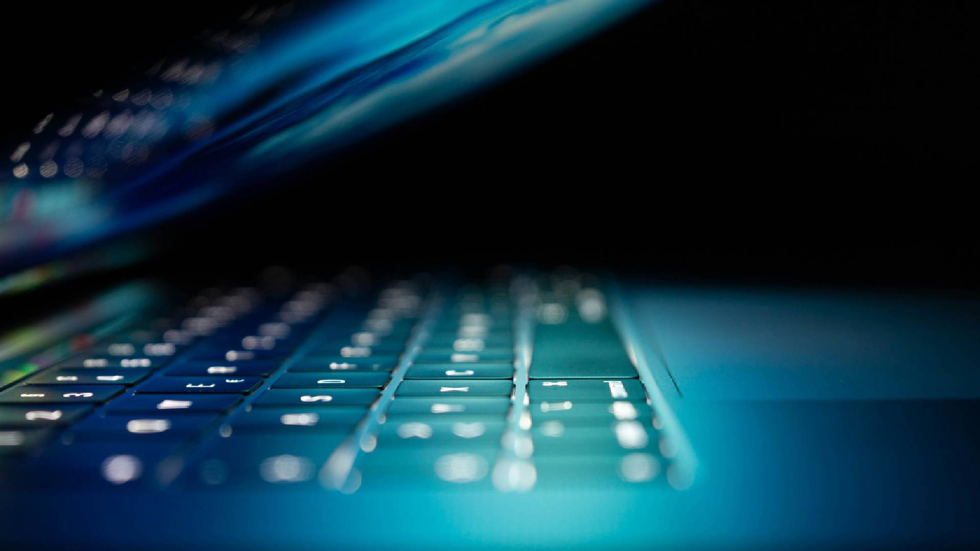 Close up of a laptop keyboard with blue digital lighting.