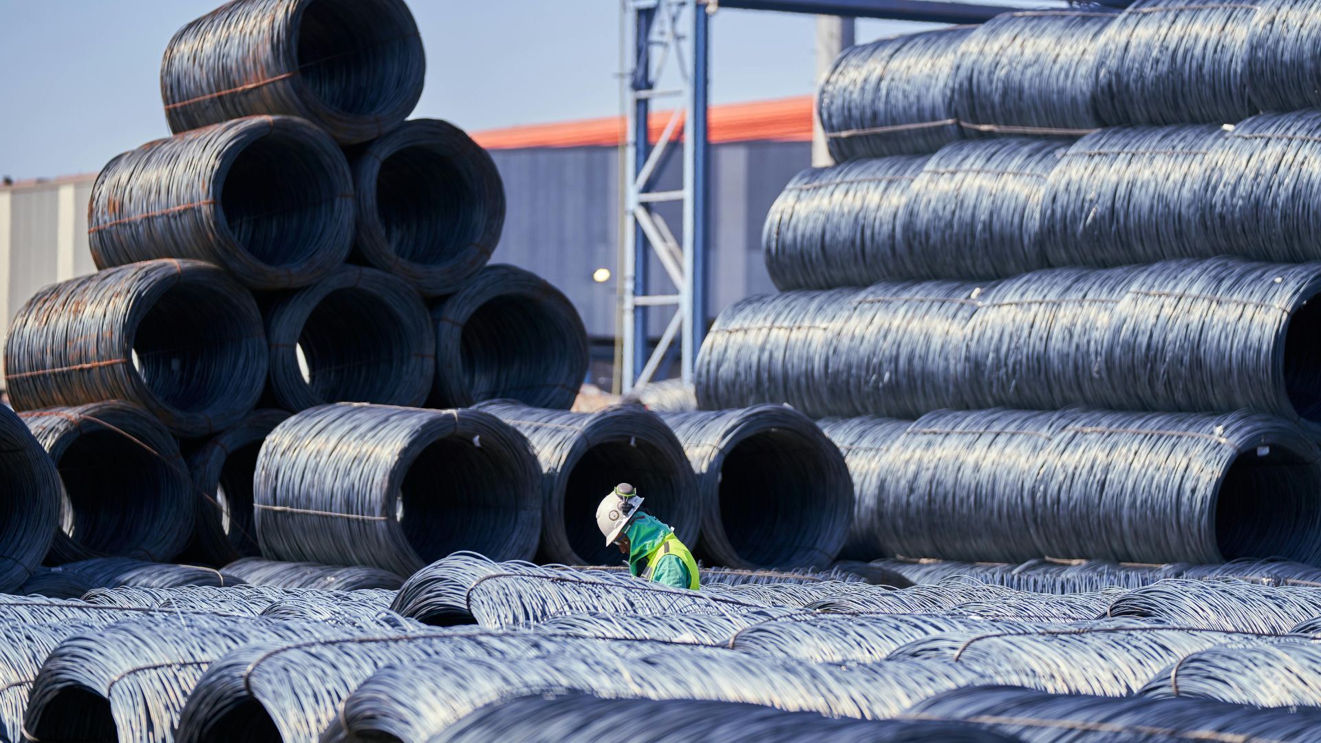 Industrial Worker Among Stacked Steel Coils in Warehouse