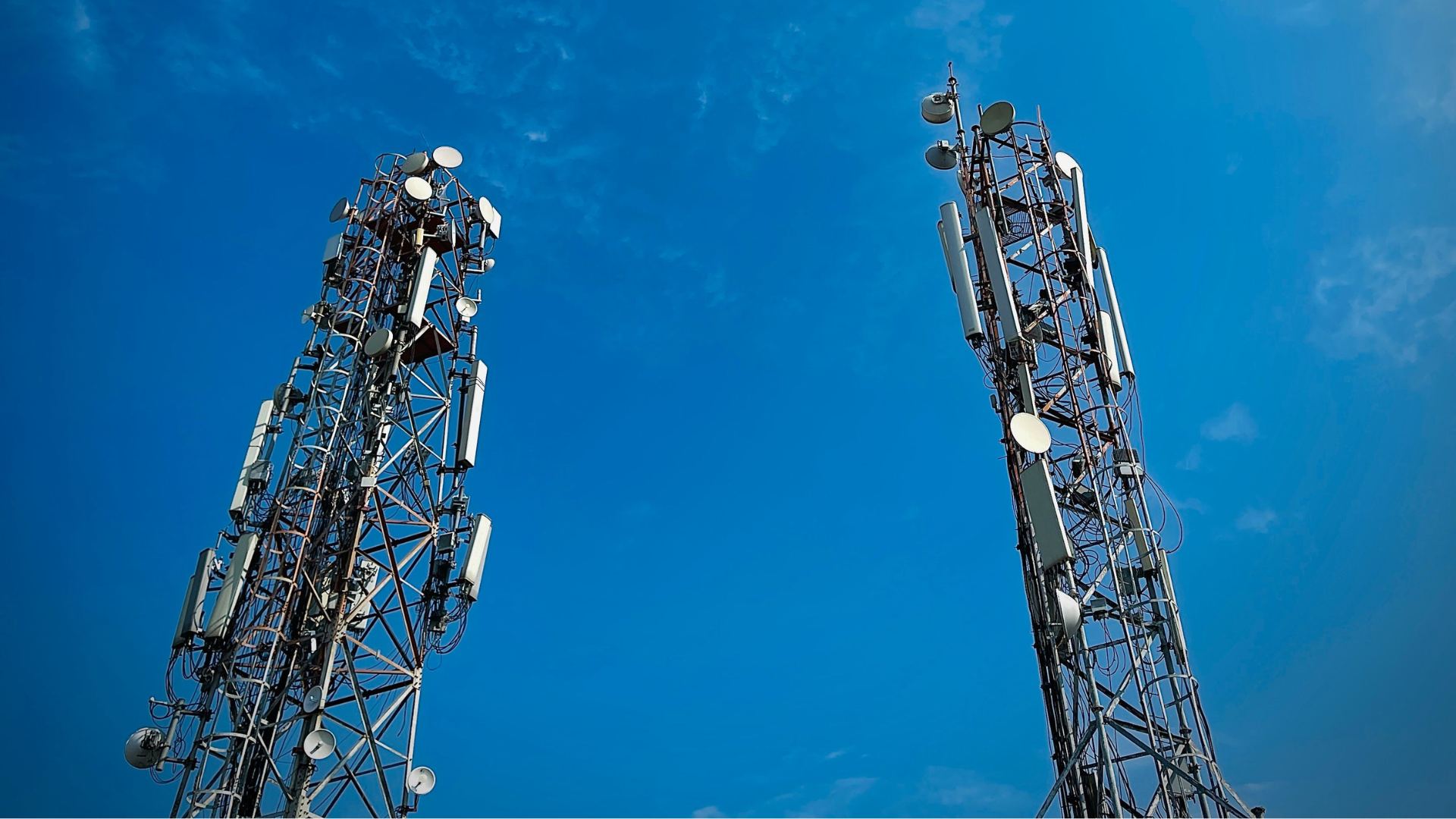 Two telecommunication towers standing against a vibrant clear blue sky, showcasing modern communication technology.